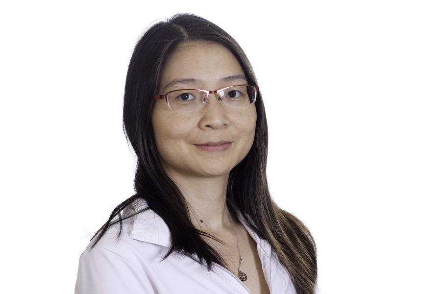 This Brian Charles Steel photo is a headshot of a woman of Asian descent.  She is wearing a white blouse, glasses, and a necklace.  Her hair is black and straight.  She is centered in the frame, and the background is completely white.  She is lit in a Rembrandt style. 